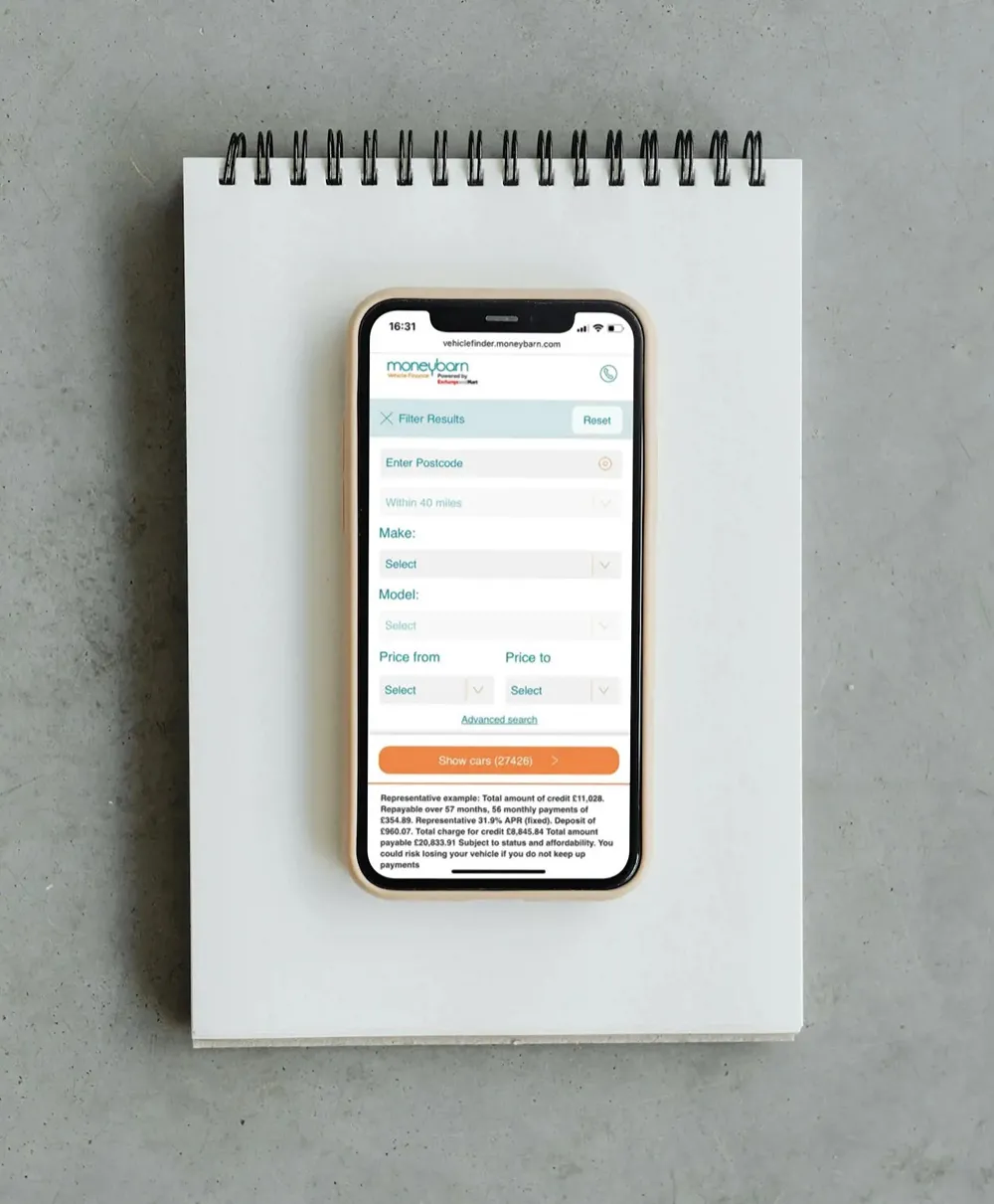 Moneybarn webpage on a smartphone device on a notepad.