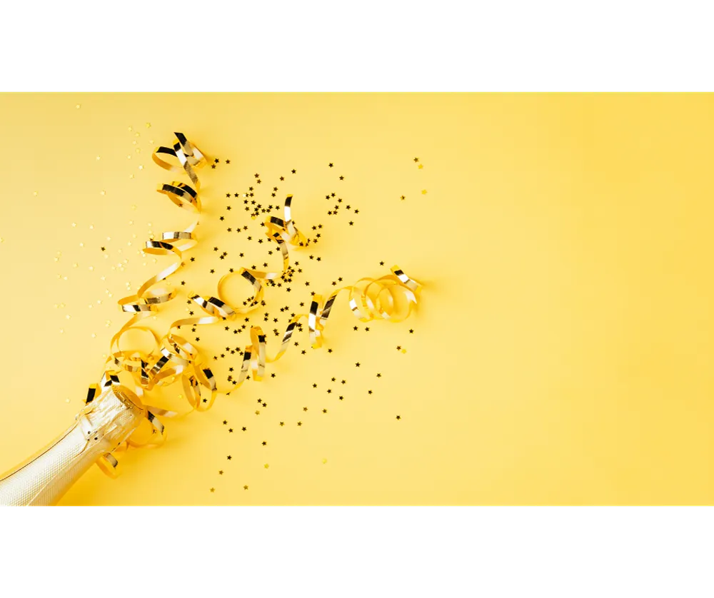 Golden party streamers arranged as if they are popping out of a champagne bottle on a yellow background