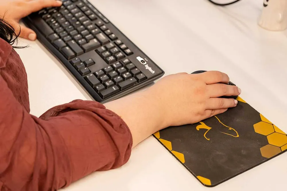 Cold Banana team member working at their desk, with a Cold Banana mousemat on the right.