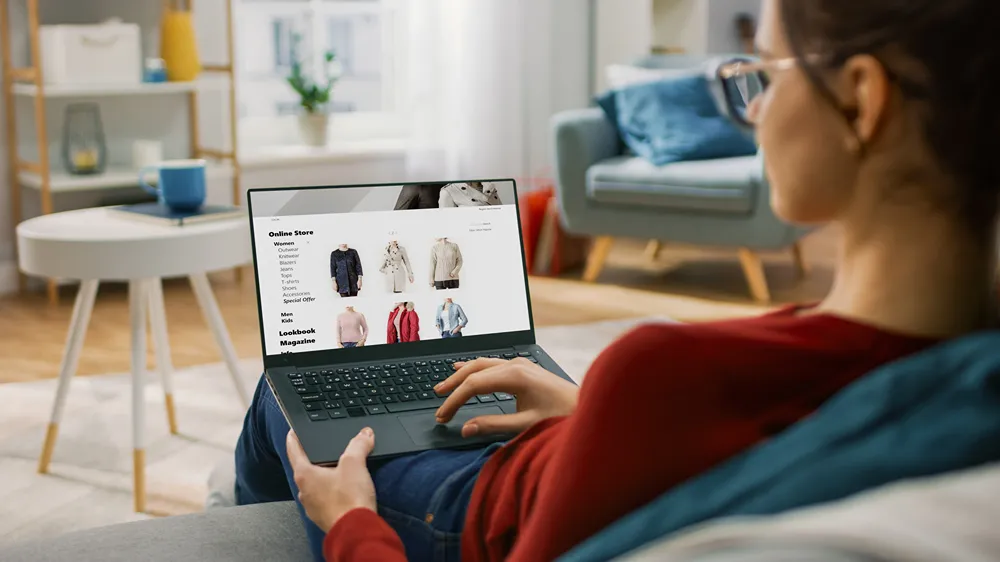 A person viewing a clothing eCommerce site on their laptop in a living room.