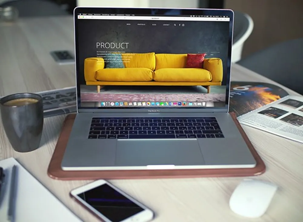 A laptop in a living room with a sofa eCommerce site open on it.
