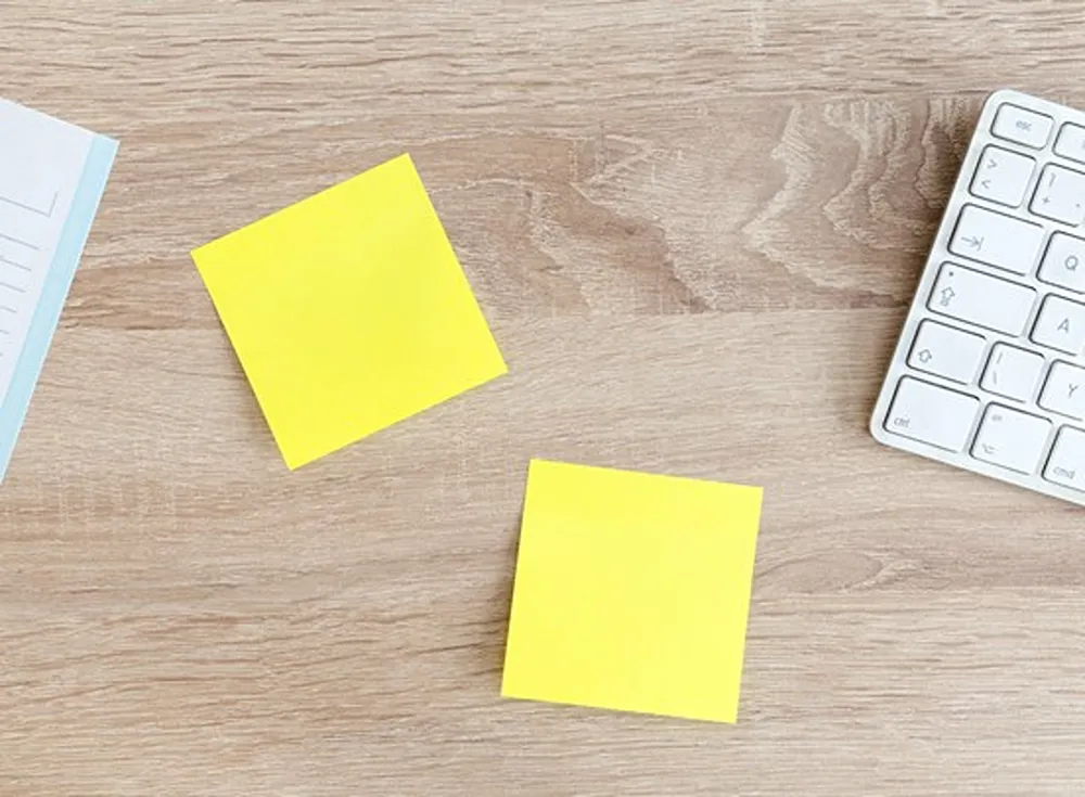 Two yellow sticky notes on a desktop.