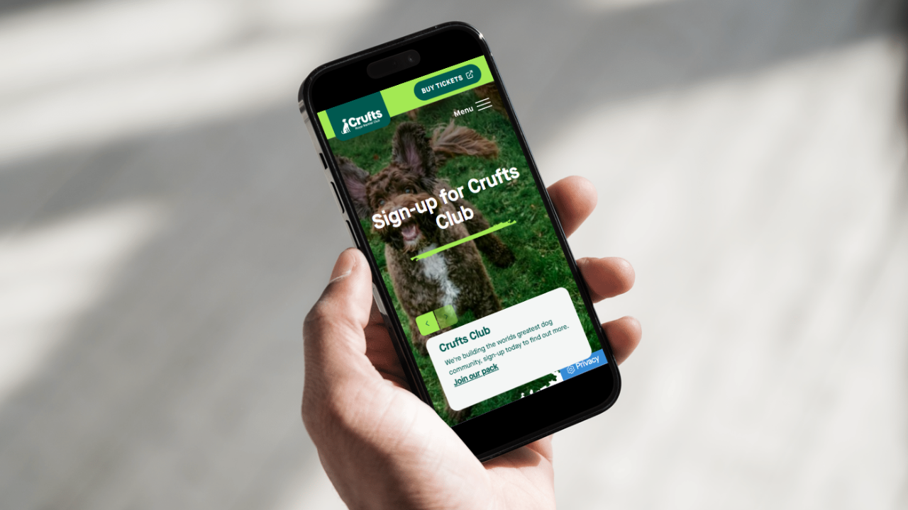 A mobile device with the Crufts website on it. The page reads "Sign up for Crufts Club"