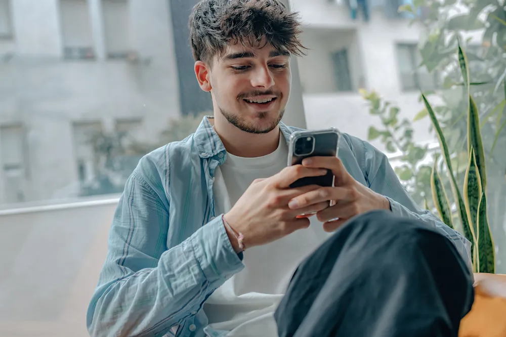 A person wearing a white t-shirt and a light blue shirt looking at their phone.