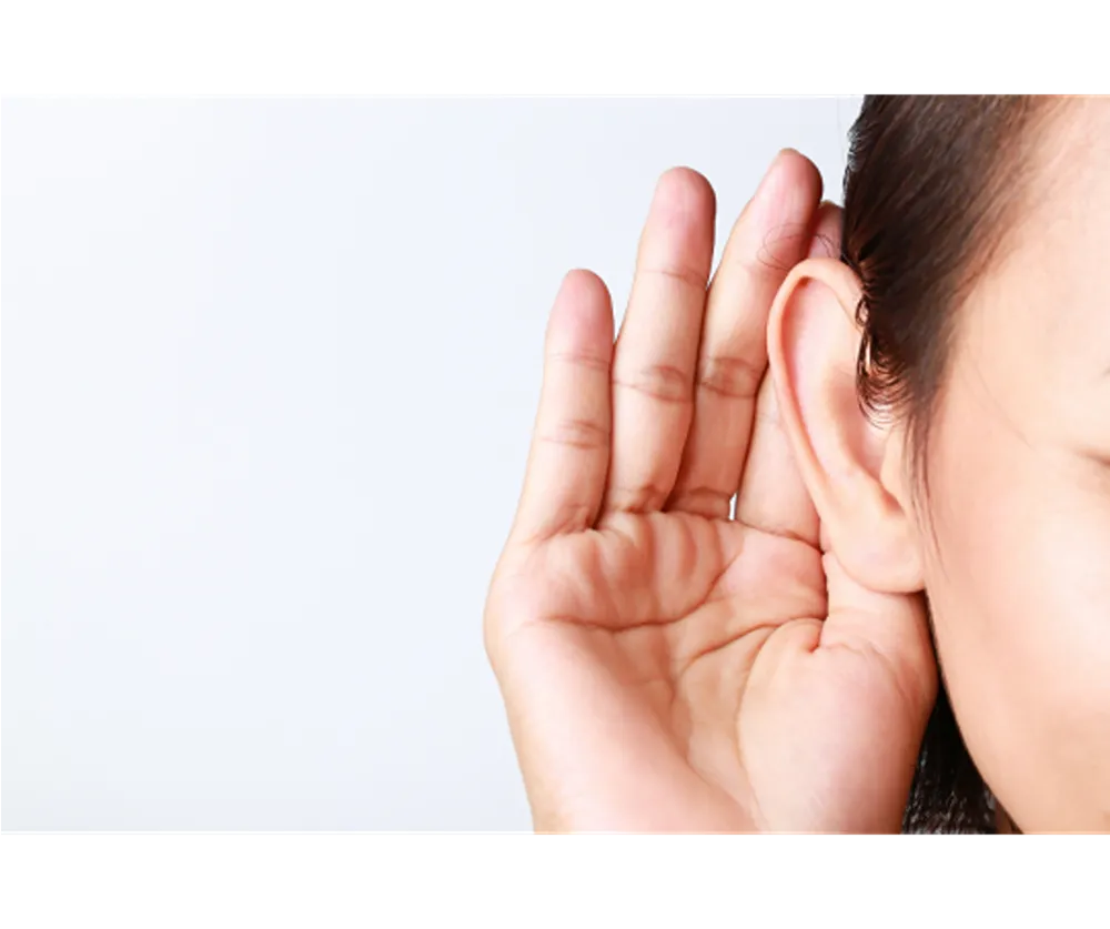A person holding their hand to their ear as if trying to listen harder to a conversation