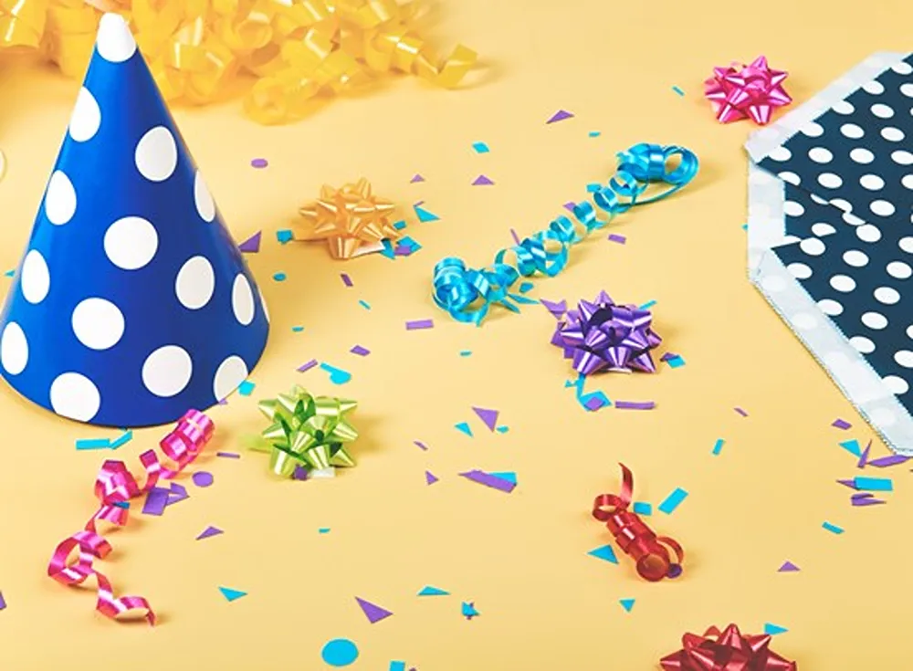 A party hat and confetti on a yellow background