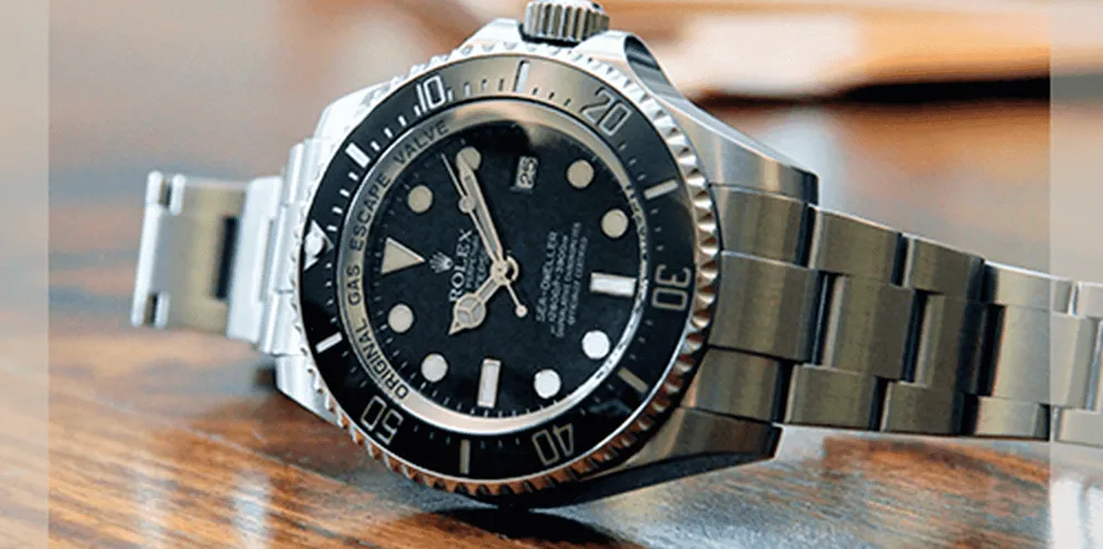 A photo of a silver Rolex on a wooden table top.