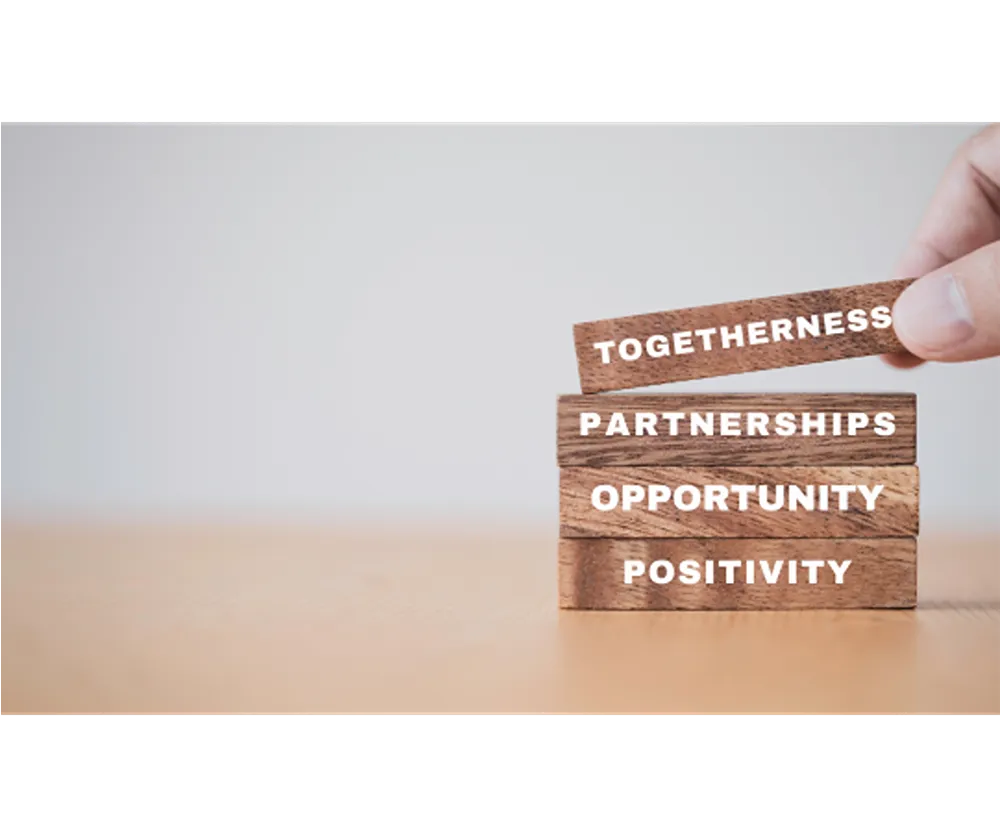 Four building blocks stacked on top of each other, reading as follows in ascending order: Positivity, Opportunity, Partnerships, Togetherness