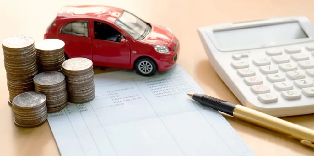 A toy car next to car keys, placed upon a car insurance contract.