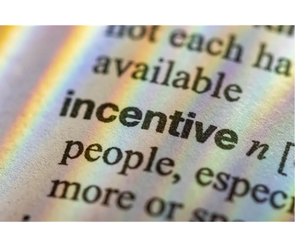 The word "incentive" in a dictionary with rainbow light from a prism spilling over it