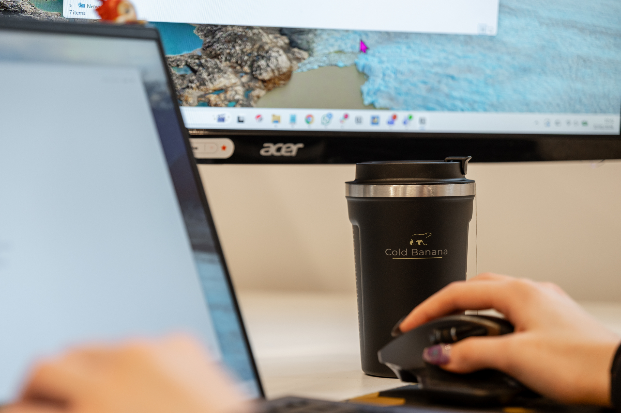 A Cold Banana mug in the background as a Cold Banana employee works at their desk