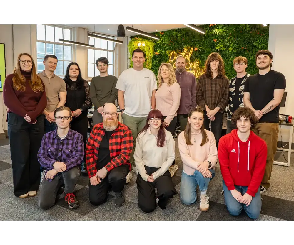 Cold Banana team posing together for the camera, 10 team members are standing at the back, with 5 team members kneeling in the front row.