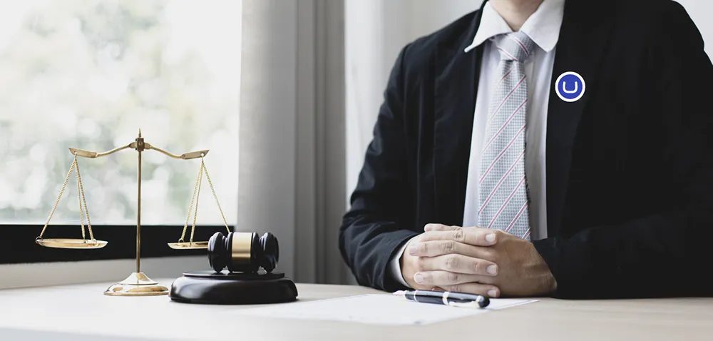 A lawyer wearing a suit sitting at his desk, with an Umbraco logo on his lapel