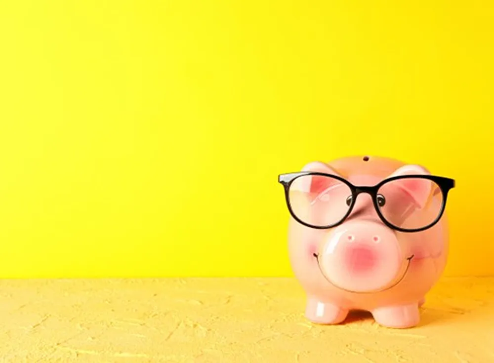 A pink piggie plank wearing black glasses in a yellow coloured room.
