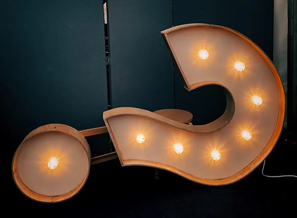 A large question mark (?) sign with lit up lightbulbs inside of it.