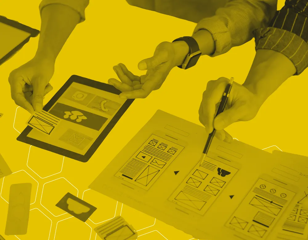 Two people discussing user interface options and pointing to printed versions of UI/UX designs