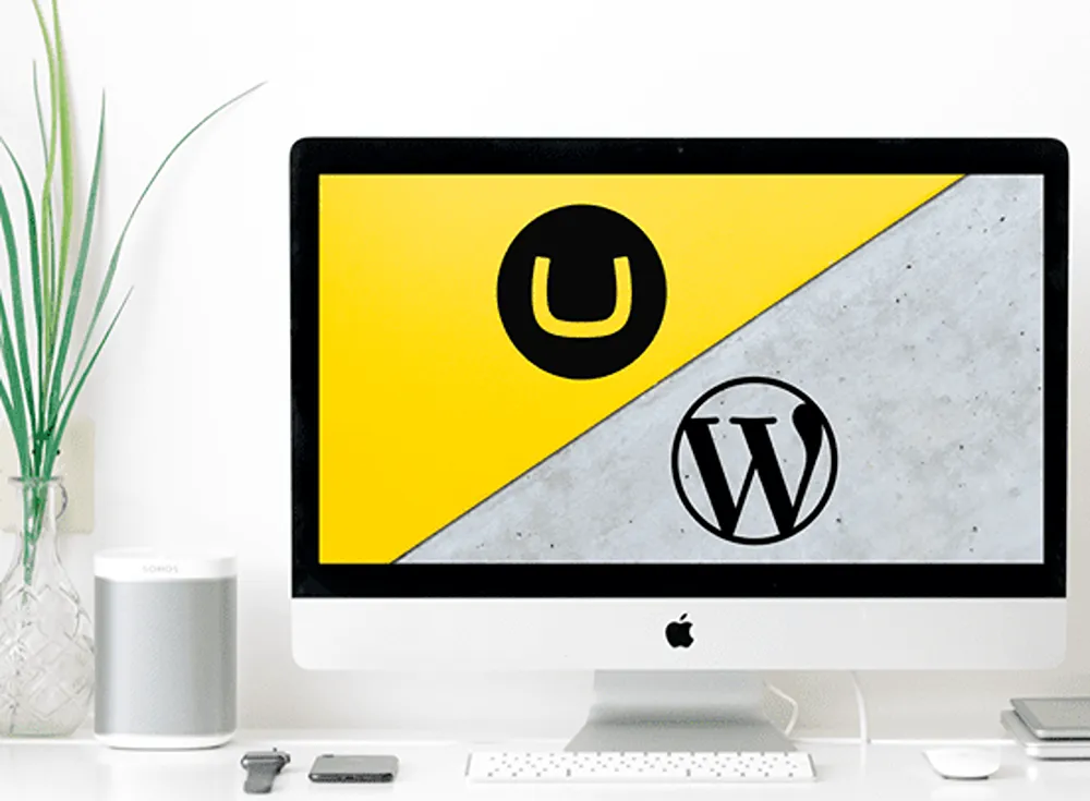 Umbraco and WordPress logos on an Apple computer desktop monitor in a home office