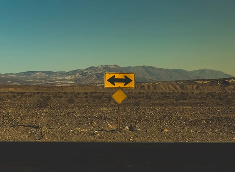 Crossroads, with a yellow sign with a black arrow pointing left and right.