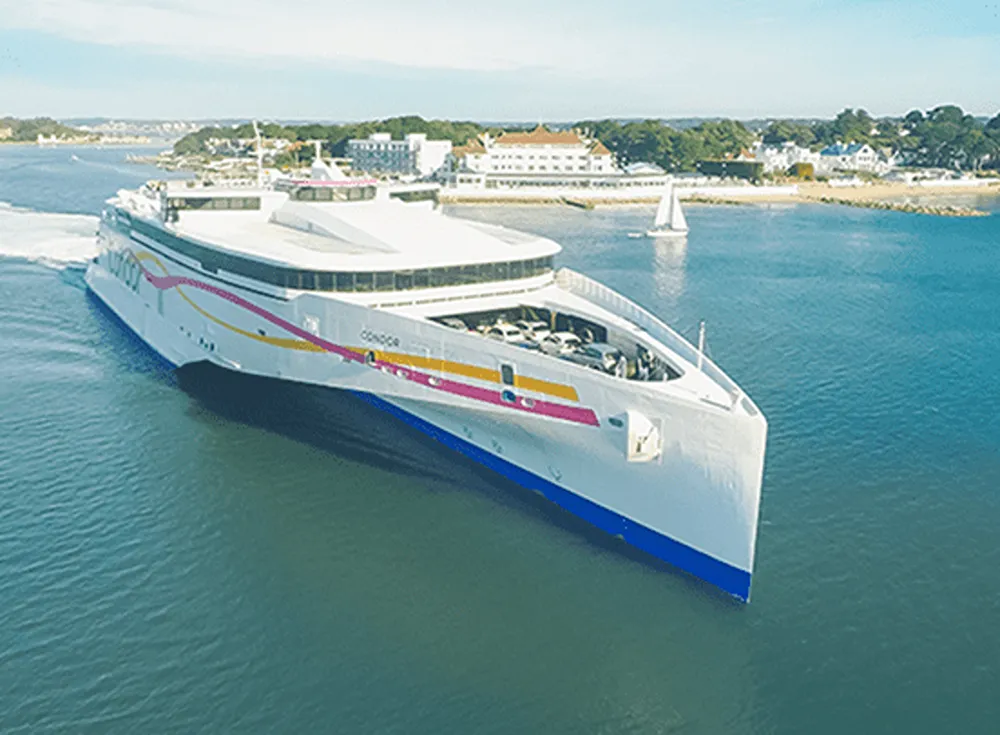 A photo of a Condor Ferry coasting on blue sea, with a port in the background