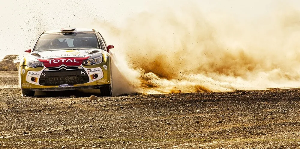 A car drifting on gravel and throwing up a cloud of dust