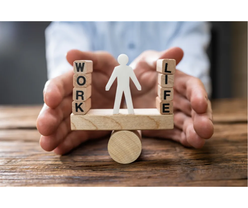 A wooden block seesaw with the words "WORK" and "LIFE" balanced on either side